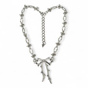 Silver necklace with a bow pendant on a white background by jagged halo jewelry
