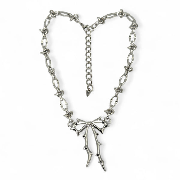 Silver necklace with a bow pendant on a white background by jagged halo jewelry