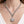 Silver chain necklace with a round pendant on a person wearing a white top.