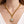 Gold chain necklace with a diamond pendant on a person wearing a white top.