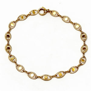 Gold bracelet with decorative links on a white background