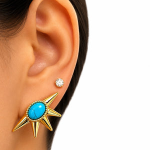 Gold star-shaped earring with turquoise stone worn by a person
