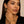 Woman wearing gold earrings and bracelet against a beige background