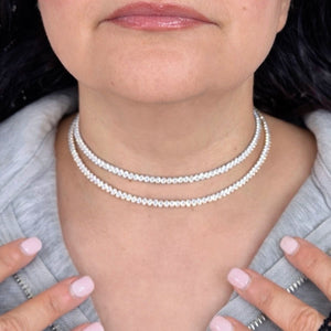 Person wearing a pearl necklace with a neutral background