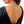 A close-up of a model's back wearing a silver chain necklace with a high-heeled shoe charm, styled with a black open-back top.