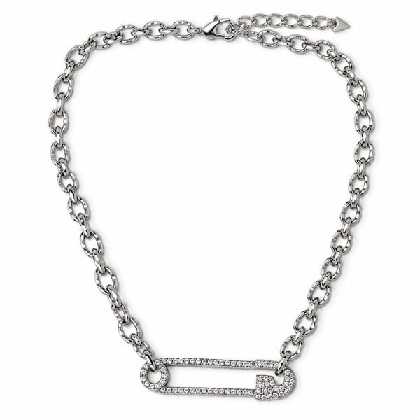 A silver-toned chain necklace featuring a safety-pin style pendant paved with small clear stones, shown on a plain white background.