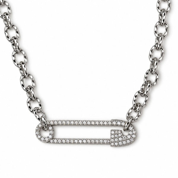 A silver-toned safety pin pendant necklace paved with small clear stones, suspended from a matching link chain on a white background.
