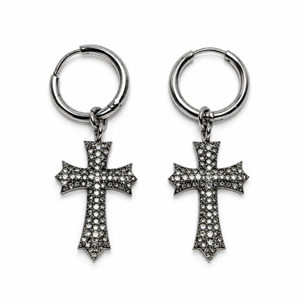 A pair of silver-toned hoop earrings with dangling cross charms, each adorned with small clear pavé stones, shown on a plain white background.