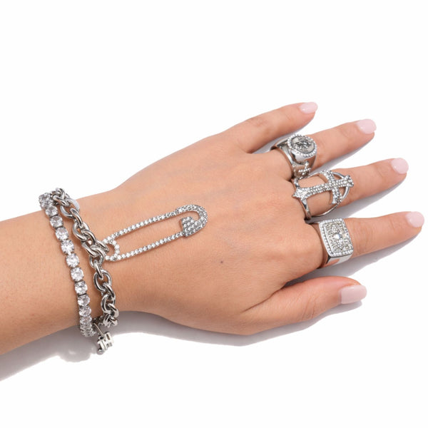 Hand wearing multiple silver rings and bracelets on a white background