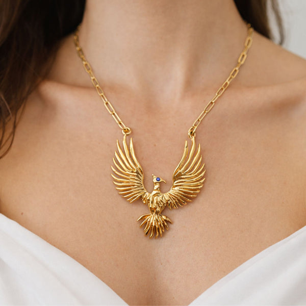 Gold eagle pendant necklace on a person wearing a white top