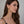 Woman wearing gold earrings with a neutral background fringe tassel