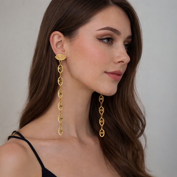 Woman wearing gold earrings with a neutral background fringe tassel