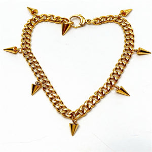 Gold chain bracelet with spike-like attachments on a white background