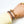 Two gold chain bracelets on a wrist with a white background
