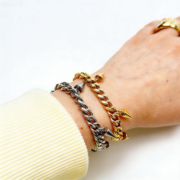 Two gold chain bracelets on a wrist with a white background