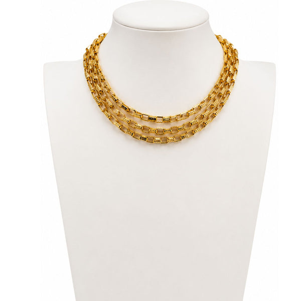 A gold multi-strand chain necklace displayed on a white jewelry bust against a white background.