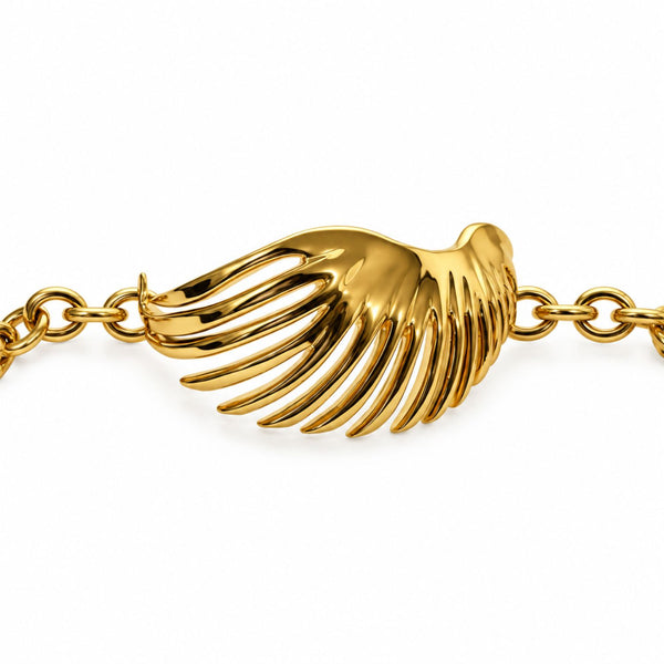 A gold wing charm bracelet with a polished, highly reflective gold-tone metal wing centerpiece and matching chain links, shown against a plain white background.