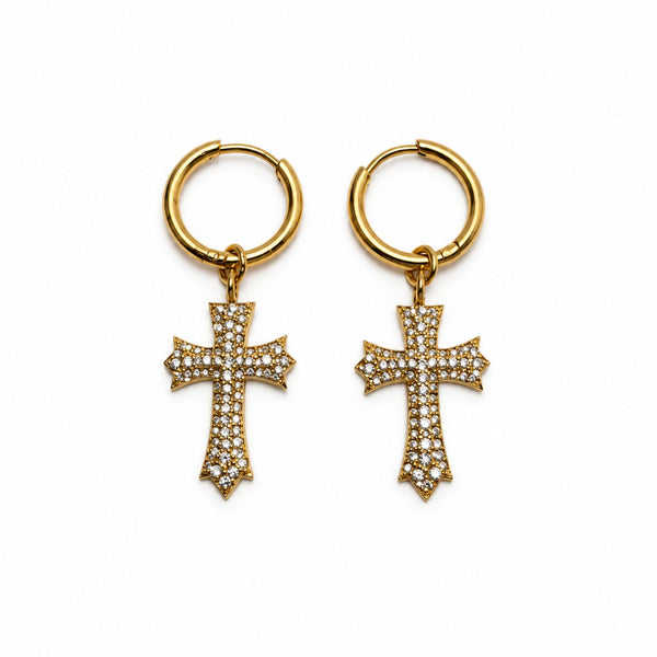 A pair of gold hoop earrings with dangling cross charms paved with small clear stones, shown on a plain white background.