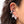A close-up of a person's ear wearing a cluster of black ear cuff studs with clear faceted gemstones, including pear-shaped and round-cut stones.