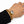 A gold chain bracelet with a large oval clear crystal pendant, shown worn on a person's wrist with a black sleeve visible.
