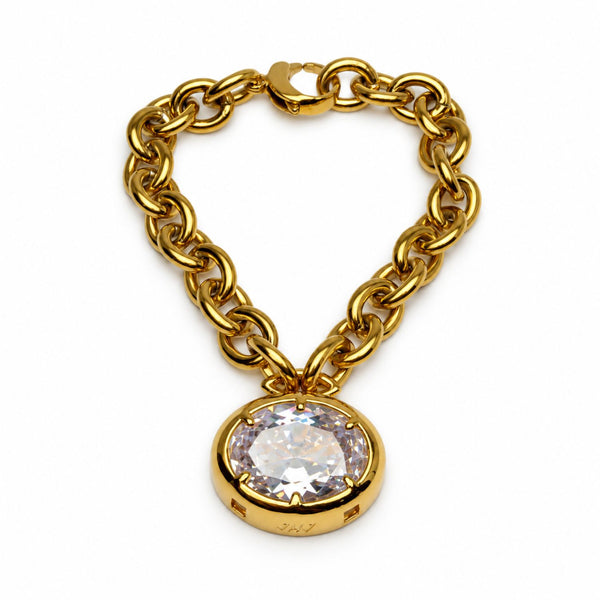 A gold chain bracelet with a large oval bezel-set clear gemstone pendant, photographed on a clean white background.