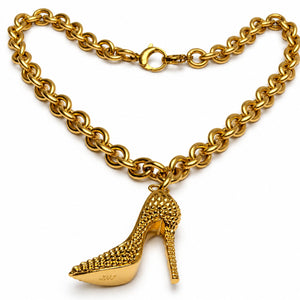 A gold-tone chain necklace featuring a dangling high-heeled shoe charm, photographed on a clean white background.